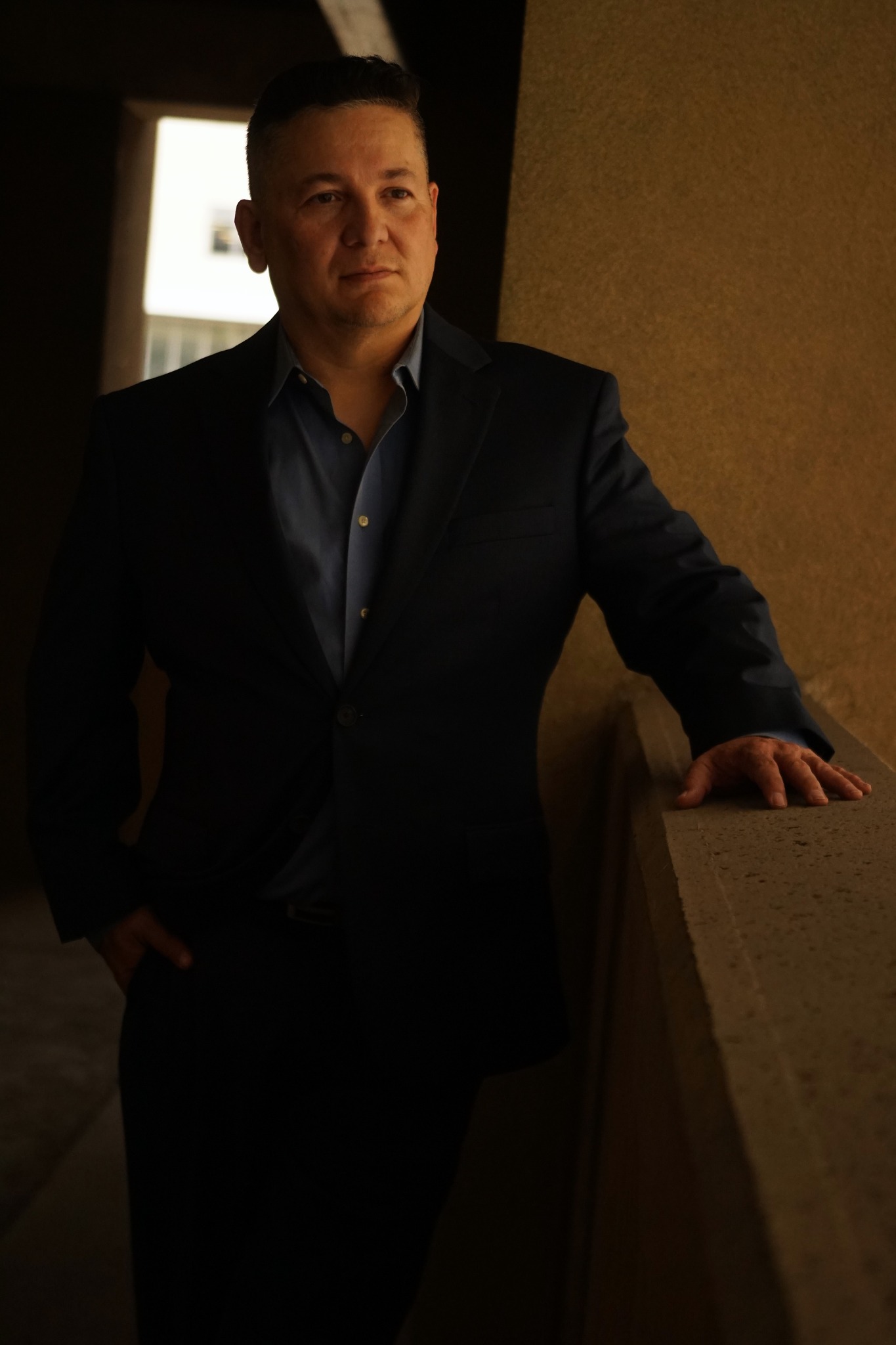 Aaron Alexander in a suit, photographed in dramatic side light